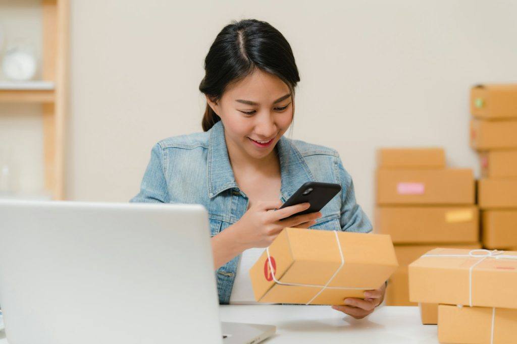 Small business owner checking a packed order beside shipping boxes