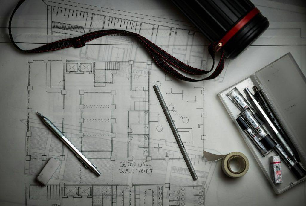 Architectural blueprints with drafting pencils, a metal ruler and plan tube