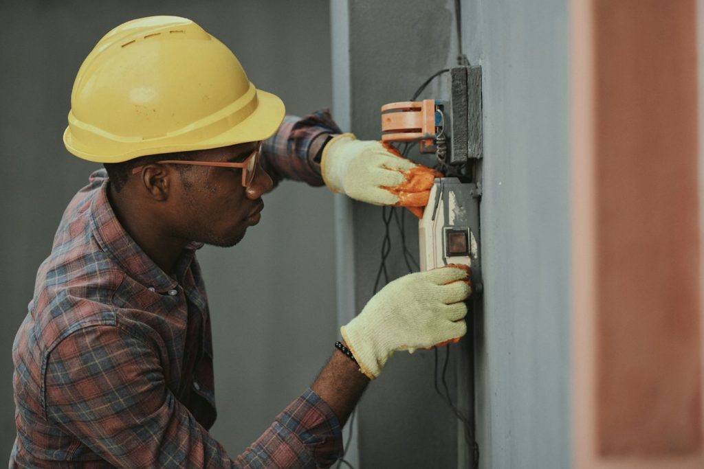 Electrician in a yellow hard hat installing wiring on a job site