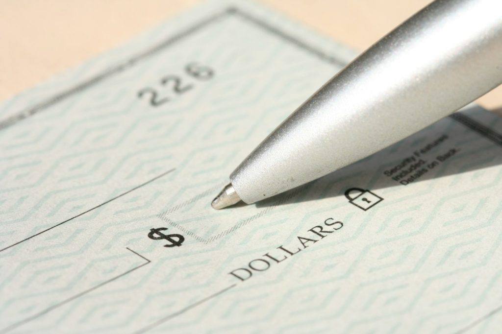 Metal ballpoint pen resting on a blank paper check