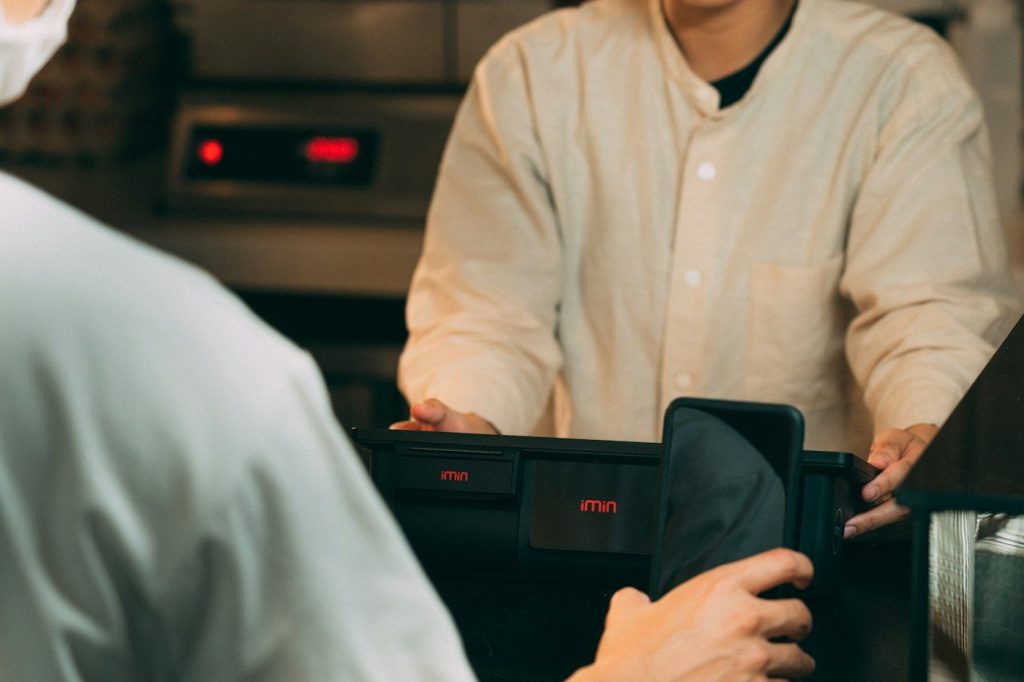 Customer paying at a point of sale terminal on a restaurant counter