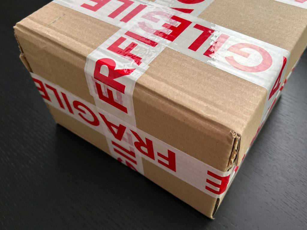 Cardboard parcel sealed with red fragile tape ready for shipping