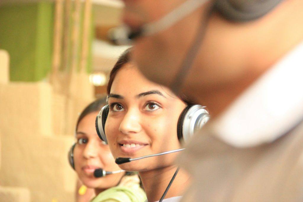 Two support agents wearing headsets working in a bright office